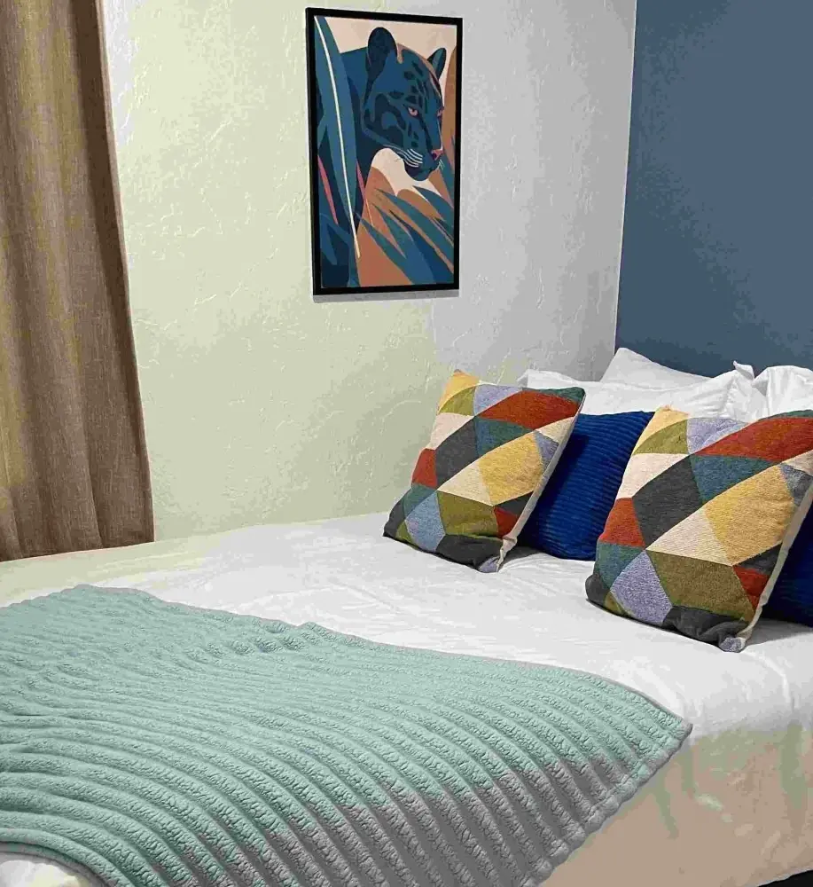 A bedroom with the bed made and the pillows set after one of our cleans