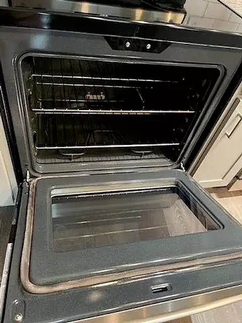 An oven with the door open, racks and walls clean