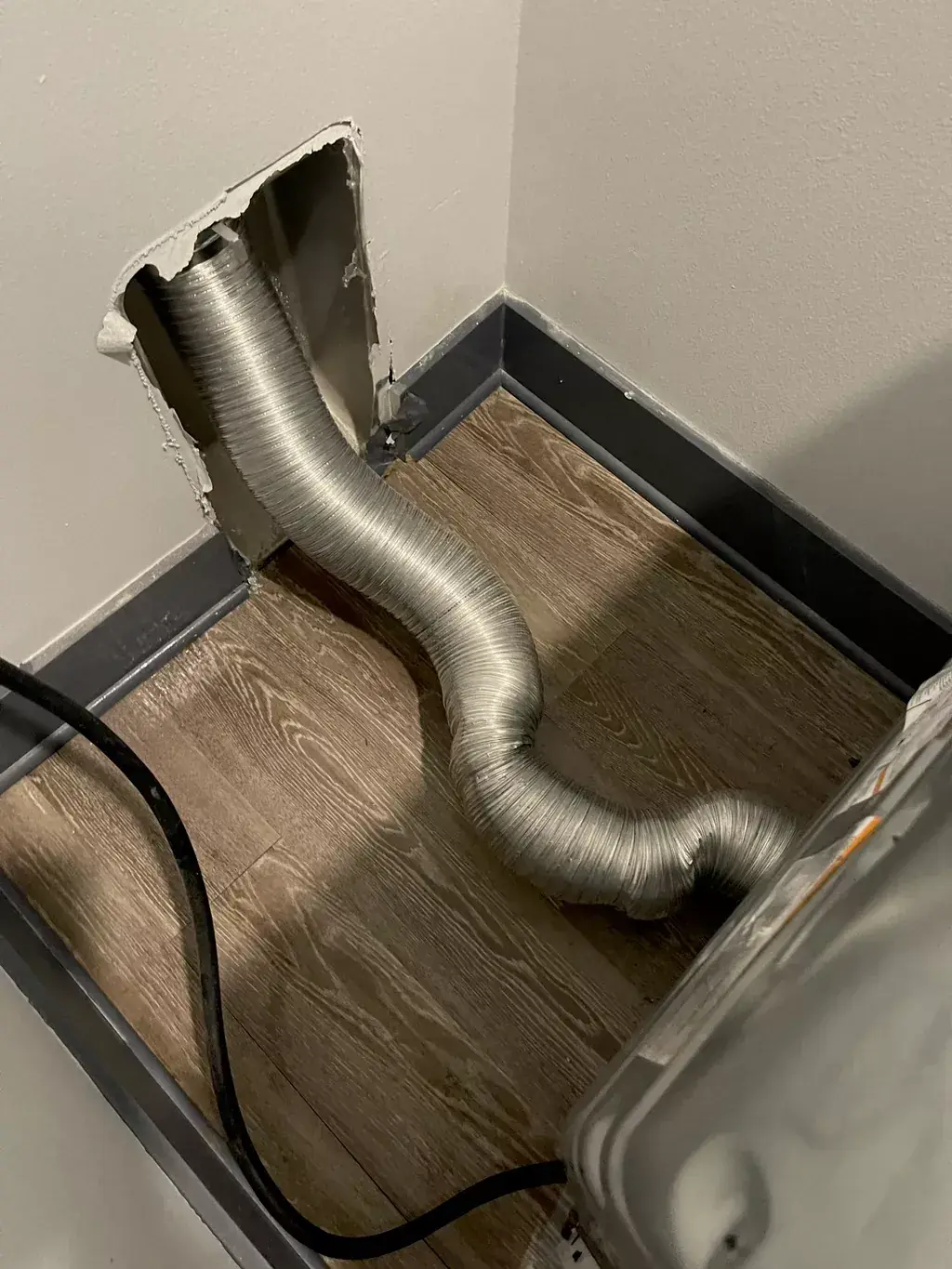 After: Dryer vent hose and floor pan in a laundry nook
