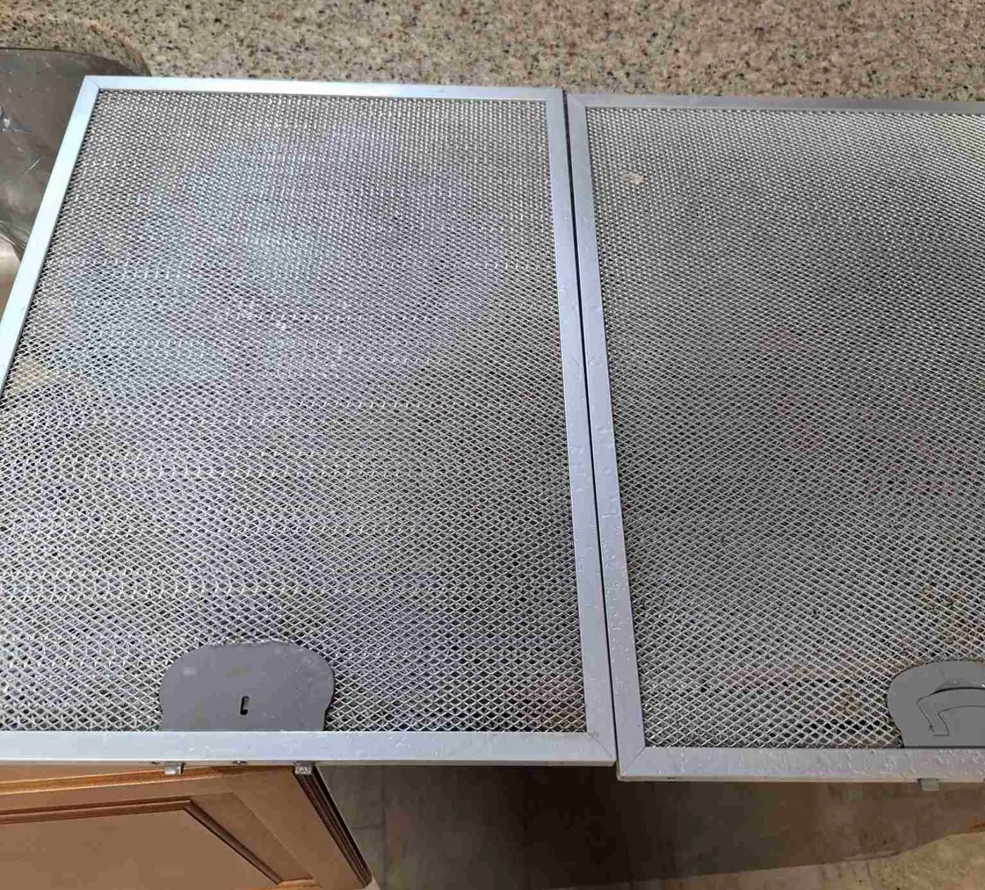 After: Two stainless steel range-hood grease filters on a kitchen counter