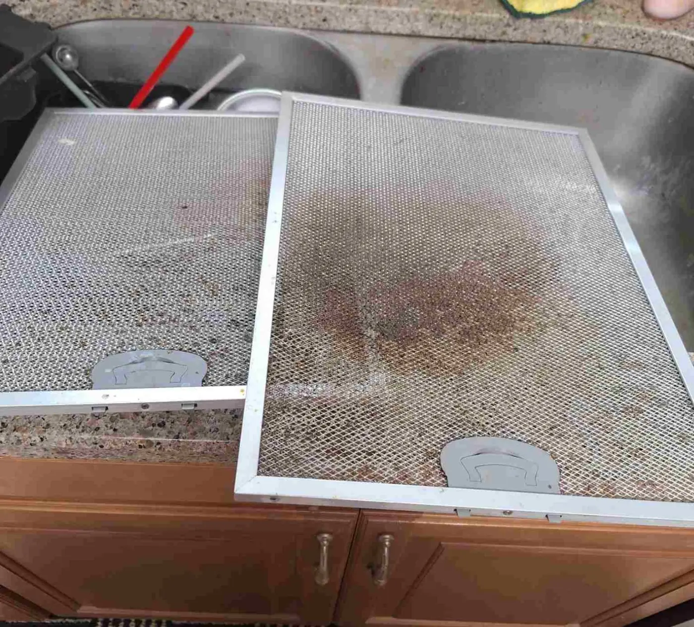 Before: Two stainless steel range-hood grease filters on a kitchen counter